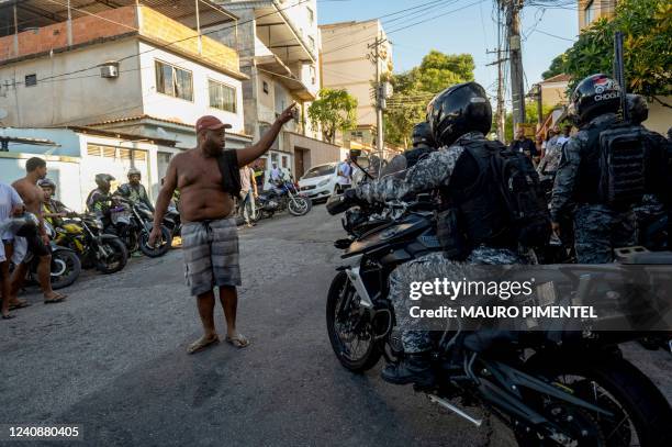 Graphic content / TOPSHOT - A man shouts at policemen outside the Getulio Vargas Hospital, after a police operation at a favela, in Rio de Janeiro,...