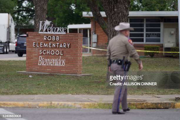 An officer walks outside of Robb Elementary School in Uvalde, Texas, on May 24, 2022. - An 18-year-old gunman killed 14 children and a teacher at an...
