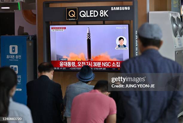 People watch a television screen showing a news broadcast with file footage of a North Korean missile test, at a railway station in Seoul on May 25...