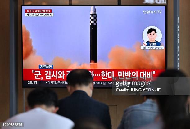 People watch a television screen showing a news broadcast with file footage of a North Korean missile test, at a railway station in Seoul on May 25...