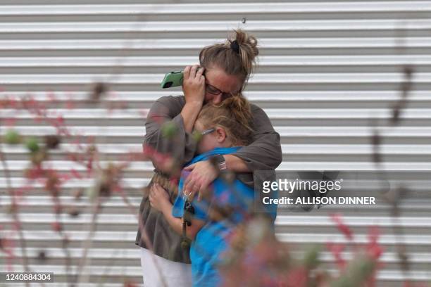 Woman cries and hugs a young girl while on the phone outside the Willie de Leon Civic Center where grief counseling will be offered in Uvalde, Texas,...
