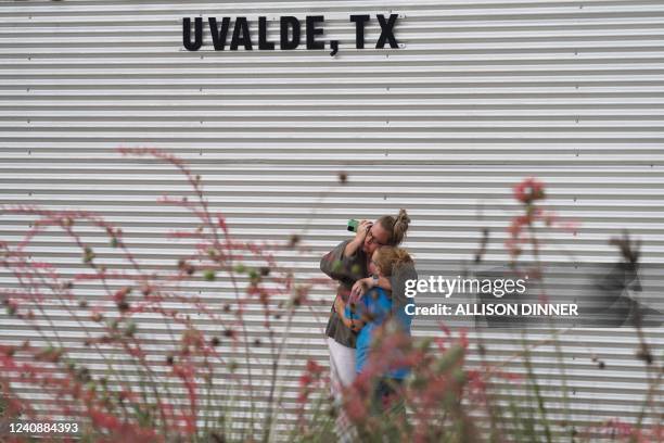 Woman cries and hugs a young girl while on the phone outside the Willie de Leon Civic Center where grief counseling will be offered in Uvalde, Texas,...