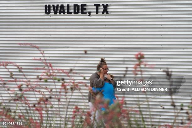 Woman cries and hugs a young girl while on the phone outside the Willie de Leon Civic Center where grief counseling will be offered in Uvalde, Texas,...