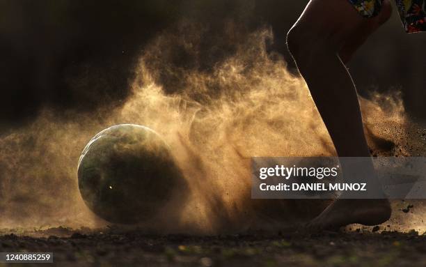 Boy plays soccer on a dusty field in Barrancas, Guajira province, Colombia, on May 22, 2022. - With bare feet on dusty fields, an indigenous man who...