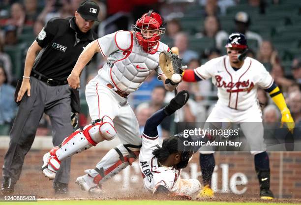 Ozzie Albies of the Atlanta Braves slides into home safely against J.T. Realmuto of the Philadelphia Phillies during the sixth inning at Truist Park...