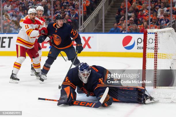 Goaltender Mike Smith of the Edmonton Oilers makes a save as Mikael Backlund of the Calgary Flames looks on during the first period in Game Four of...