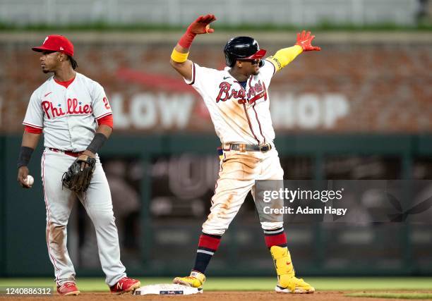 Ronald Acuna Jr. #13 of the Atlanta Braves reacts in front of Jean Segura of the Philadelphia Phillies after tying the game during the ninth inning...
