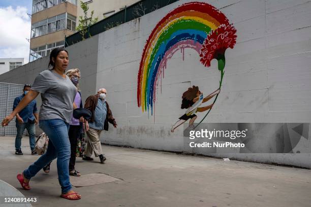 People are seen walking near a mural alluding to the fight against COVID-19, in the city downtown. Lisbon, May 23, 2022. Portugal is the European...