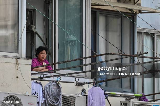 Resident looks out from her window during a Covid-19 coronavirus lockdown in the Jing'an district of Shanghai on May 25, 2022.