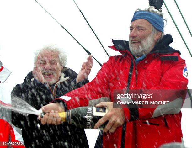 Le navigateur français Jean-Luc Van Den Heede ouvre une bouteille de champagne sous les yeux du chanteur Hugues Aufray , le 11 mars 2004, lors de son...