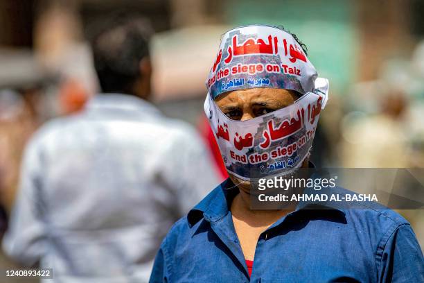 Demonstrator looks on while his head is wrapped in a banner reading in Arabic and English "end the siege on Taiz [Taez]" demanding the end of a...
