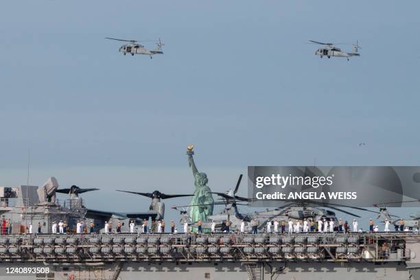 Sailors and Marines stand on the flight deck of the USS Bataan as the ship passes the Statue of Liberty during Fleet Week in New York Harbor on May...