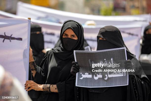 Woman holds a sign reading in Arabic "end the siege on Taez" demanding the end of a years-long blockade of the area imposed by Yemen's Huthi rebels...