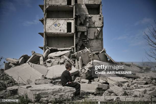 Young boy sits in front of a damaged building after a strike in Kramatorsk in the eastern Ukranian region of Donbas, on May 25, 2022.