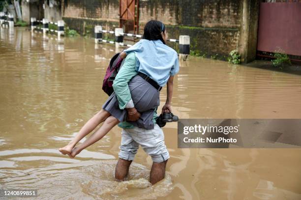 Man returns his daughter from school wades across a flooded street after heavy rains, in Guwahati, Assam, India on 25 May 2022. Waterlogging is a...