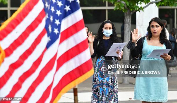 People hold US flags and gesture while attending their Naturalization Oath ceremony for US citizenship in Los Angeles, California, on May 25, 2022.