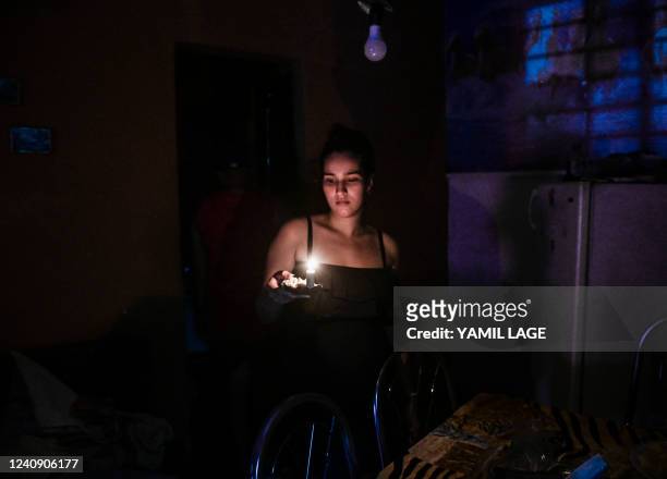 Woman holds a candle during a blackout in Havana, on May 25, 2022. - The main thermoelectric central of Cuba was reached Tuesday by a lightning that...