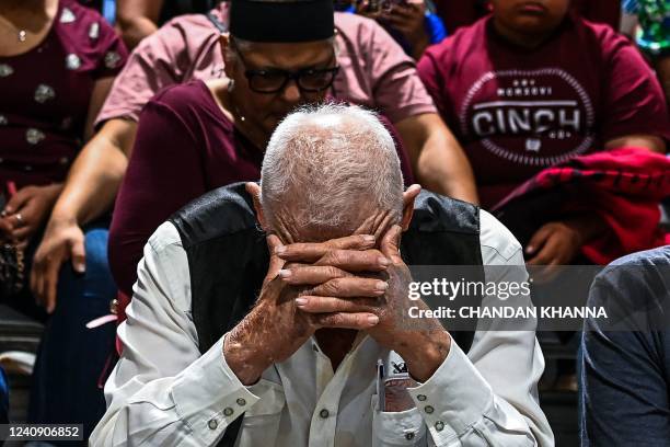 People from the community gather as they mourn during a vigil for the victims of the mass shooting at Robb Elementary School in Uvalde, Texas on May...