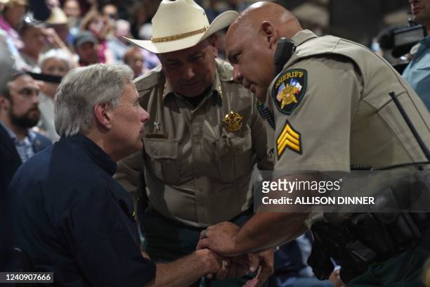 Uvalde County Sheriff Ruben Nolasco and another local police officer shake hand with Texas Governor Greg Abbott as they attend a vigil for the...