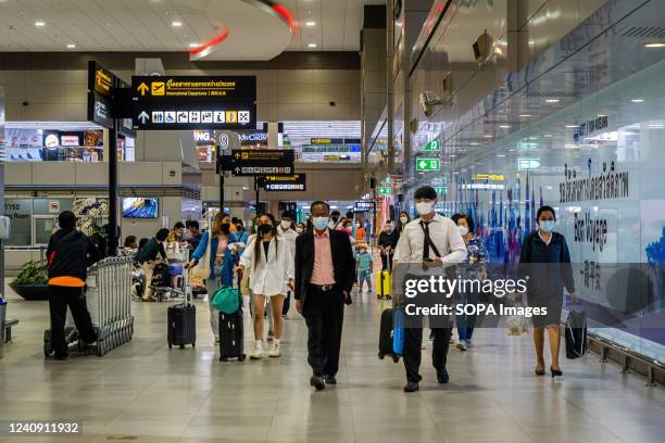Travelers wearing face masks walk toward security checkpoints in the domestic departure hall at Don Mueang International Airport in Bangkok....