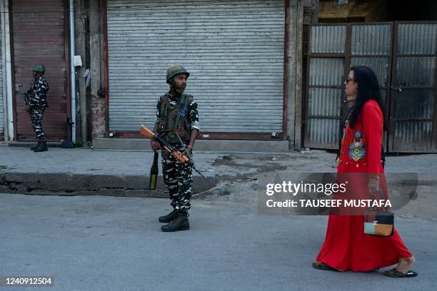 Indian tourists walk past Indian paramilitary troopers standing guard in front of closed shops during the second day of a spontaneous strike in parts...