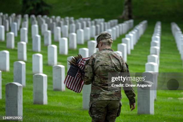 Member of the 3rd U.S. Infantry Regiment places flags at the headstones of U.S. Military personnel buried at Arlington National Cemetery, in...