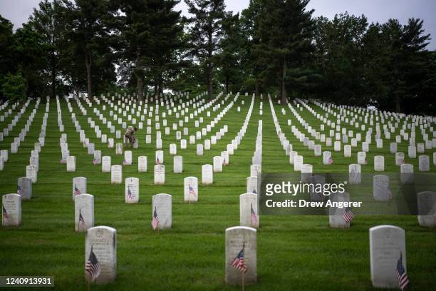 Member of the 3rd U.S. Infantry Regiment places flags at the headstones of U.S. Military personnel buried at Arlington National Cemetery, in...