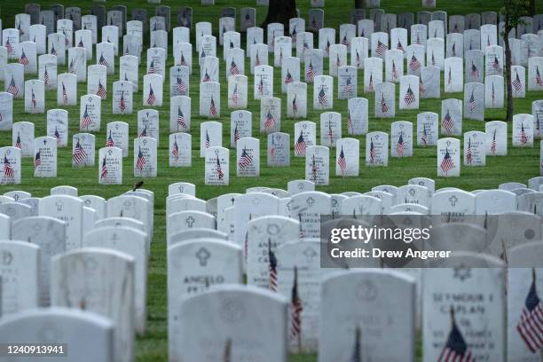 Flags stand at the headstones of U.S. Military personnel buried at Arlington National Cemetery, in preparation for Memorial Day, on May 26, 2022 in...