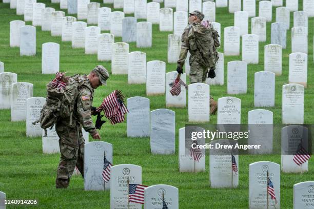 Members of the 3rd U.S. Infantry Regiment place flags at the headstones of U.S. Military personnel buried at Arlington National Cemetery, in...