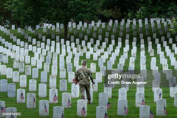 Member of the 3rd U.S. Infantry Regiment places flags at the headstones of U.S. Military personnel buried at Arlington National Cemetery, in...