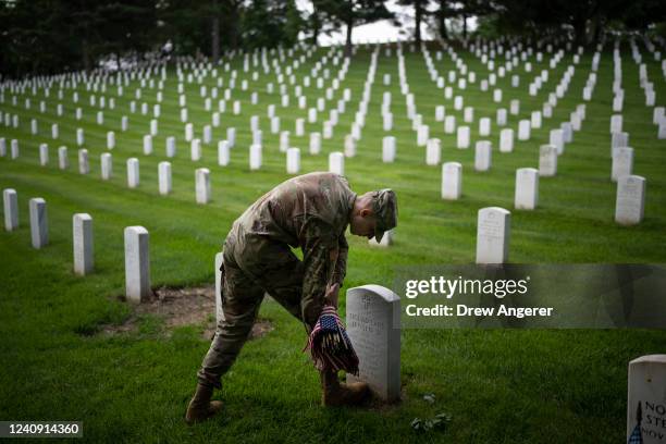 Member of the 3rd U.S. Infantry Regiment places flags at the headstones of U.S. Military personnel buried at Arlington National Cemetery, in...