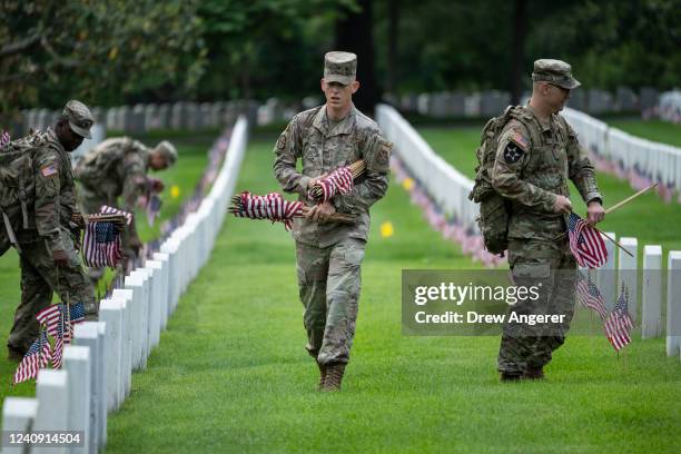 Members of the 3rd U.S. Infantry Regiment place flags at the headstones of U.S. Military personnel buried at Arlington National Cemetery, in...