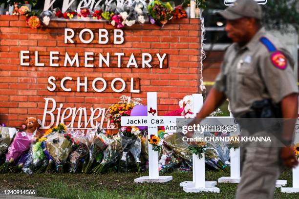 Police officers walk past a makeshift memorial for the shooting victims at Robb Elementary School in Uvalde, Texas, on May 26, 2022. - Grief at the...