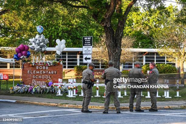 Police officers stand near a makeshift memorial for the shooting victims at Robb Elementary School in Uvalde, Texas, on May 26, 2022. - Grief at the...