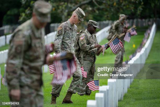 Members of the 3rd U.S. Infantry Regiment place flags at the headstones of U.S. Military personnel buried at Arlington National Cemetery, in...