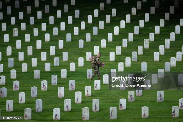 Member of the 3rd U.S. Infantry Regiment places flags at the headstones of U.S. Military personnel buried at Arlington National Cemetery, in...