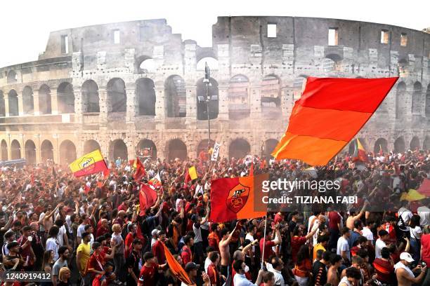 Roma's supporters celebrate during a players' bus parade in front the Colisseum and Roman Forum in Rome on May 26 a day after winning the UEFA...
