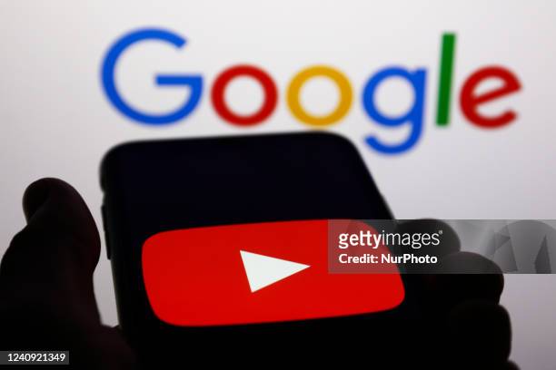 YouTube logo displayed on a phone screen and Google logo displayed on a screen in the background are seen in this illustration photo taken in Krakow,...