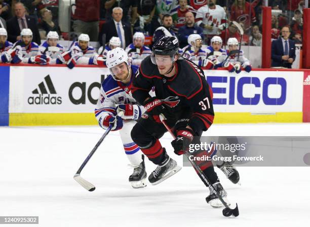 Andrei Svechnikov of the Carolina Hurricanes skates with the puck as Adam Fox of the New York Rangers looks to defend in Game Five of the Second...