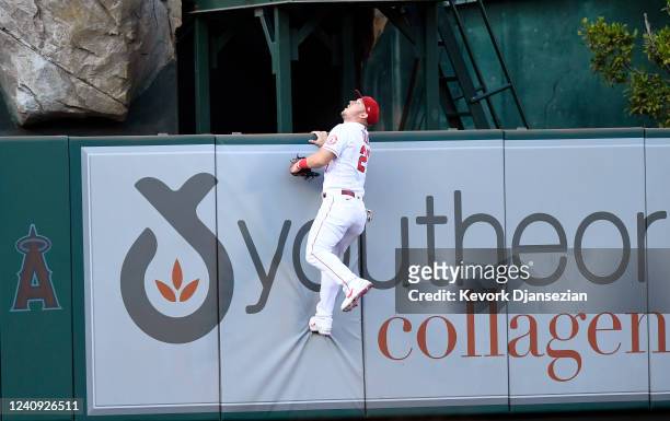Mike Trout of the Los Angeles Angels climbs up the center field wall as he chases the lead off solo home run hit by George Springer of the Toronto...