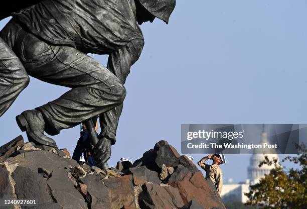 Standing on top of the base, a military member salutes the flag at the United States Marine Corps War Memorial or Iwo Jima Memorial on Wednesday...