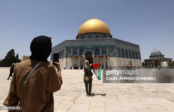 Girl poses for a picture with the Palestinian flag in front of the Dome of the Rock mosque inside Jerusalem's Al-Aqsa Mosque complex, on May 27,...