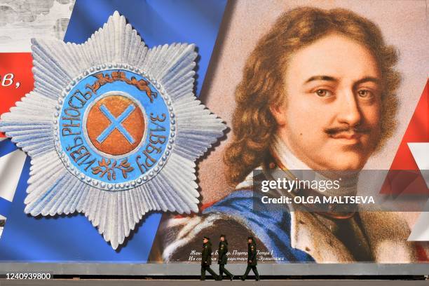 Russian service members walk in front of a giant banner depicting Peter the Great, the founder of Saint Petersburg, during the celebrations marking...