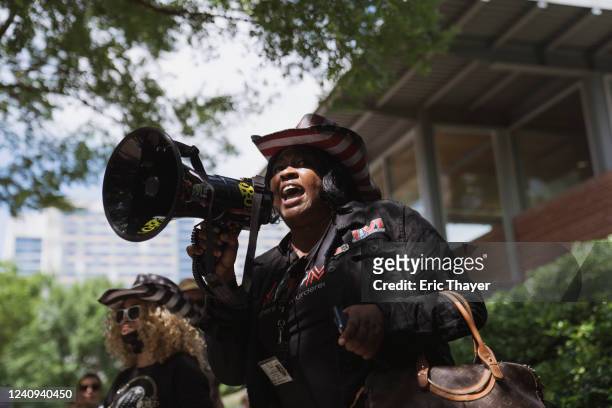 Woman yells through a megaphone during a protest across from the National Rifle Association Annual Meeting at the George R. Brown Convention Center,...
