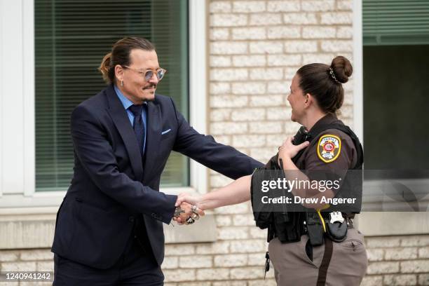 Actor Johnny Depp shakes hands with a police officer as he departs the Fairfax County Courthouse on May 27, 2022 in Fairfax, Virginia. Closing...