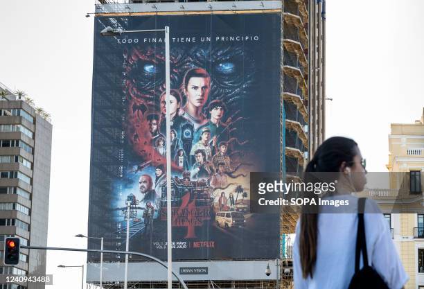 Woman stands opposite of a large street advertisement billboard from the American global on-demand Internet streaming media provider Netflix...