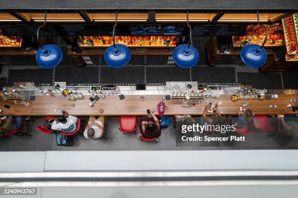 People sit at the bar at John F. Kennedy Airport at the start of the Memorial Day weekend on May 27, 2022 in New York City. The holiday weekend is...