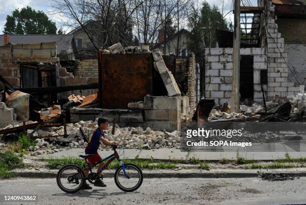 Teenager rides past a destroyed house that was damaged as a result of the shelling of the Russian army in the village of Gorenka. Russia invaded...