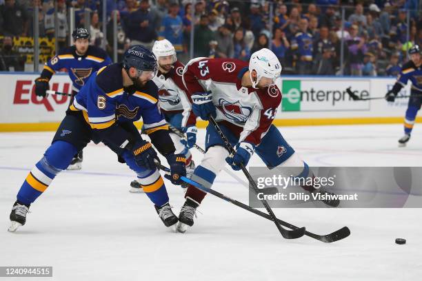 Marco Scandella of the St. Louis Blues fights Darren Helm of the Colorado Avalanche for control of the puck in the second period at Enterprise Center...