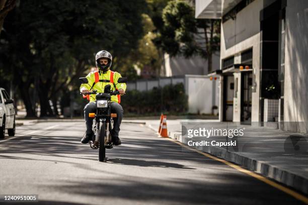 delivery biker arriving at destination - motoboy - motoboy stock pictures, royalty-free photos & images